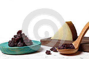 Raisins on a wooden plate and in a spoon and cheese