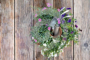 Rake and gardening shovel amidst potted flowers on wooden