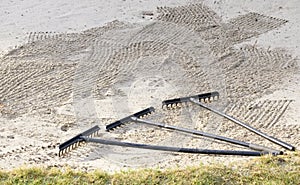 Rake in sand bunker at golf links course green for golfers