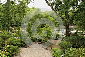 Raked stone garden surrounded by manicured shrubs and trees with a lake in the background in Janesville, Wisconsin