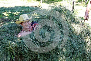 Woman laying in the hay. Putting the grass on the trailor. Farm chores, working on a field.