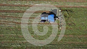 Raking hay with a double wheel rake tractor on a sunny day aerial view