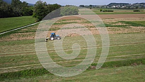 Raking hay with a double wheel rake tractor on a sunny day aerial view
