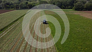 Raking hay with a double wheel rake tractor on a sunny day aerial view