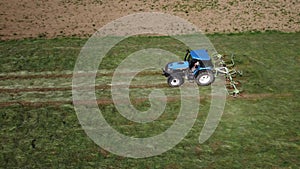 Raking hay with a double wheel rake tractor on a sunny day aerial view