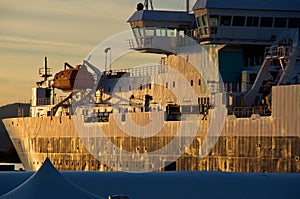 The raking light of the setting sun brings out all the dents and scrapes in the hull of a ship