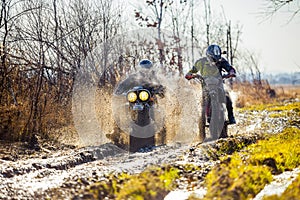 Rally motorbike rider is ahead of another on a dirt road