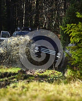 Rallying, competition and four wheel drive concept. Sport utility vehicle or SUV crossing puddle with dirt splash