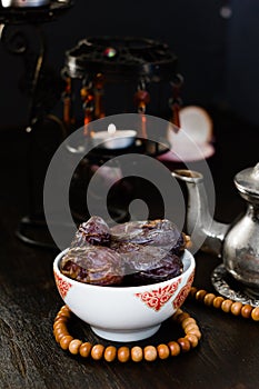 Ramadan fasting - dates for iftar in bowl on wooden table.