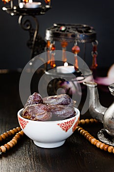 Ramadan fasting - dates for iftar in bowl on wooden table.