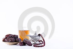 Ramadan food and drinks concept. Arabian lamp with wood rosary, dates fruit and tea on white background