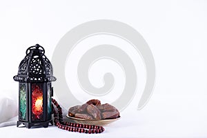 Ramadan food and drinks concept. Ramadan Lantern with arabian lamp, wood rosary, tea, dates fruit and lighting on a wooden table