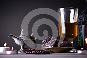 Ramadan food and drinks concept. Ramadan Lantern with arabian lamp, wood rosary, tea, dates fruit and lighting on a wooden table