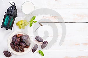 Ramadan food and drinks concept. Ramadan Lantern with Milk, dates fruit, grape and Mint leaves on a white wooden table background