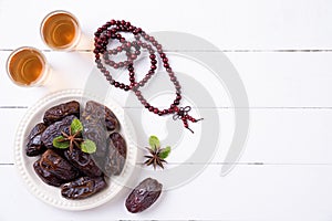 Ramadan food and drinks concept. Wood rosary, tea and dates fruit on a white wooden table background. Top view, Flat lay