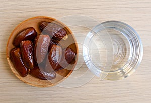 Ramadan iftar food, date fruits and glass od water on wooden table