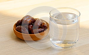 Ramadan iftar food, date fruits and glass od water on wooden table