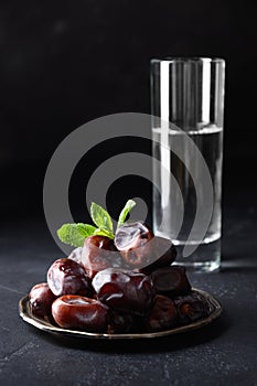 Ramadan Iftar food. Dates fruits and glass of water. Close up. Vertical format. Kareem