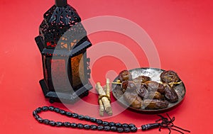 Ramadan kareem concept with dates and lanterns and rosary, siwak on red.