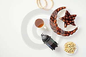 Ramadan Kareem concept. Flat lay composition with dried dates, Islamic lantern, cup of tea, rosary, nuts on white table