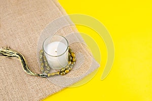 Ramadan Kareem Festival. Candle and rosary on yellow background. Happy ramadan hoilday. Copy space