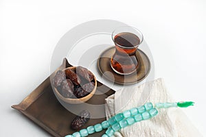 Ramadan Kareem Festival, Dates on wooden bowl with cup of black tea and rosary on white  background