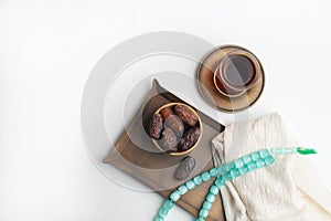 Ramadan Kareem Festival, Dates on wooden bowl with cup of black tea and rosary on white  background