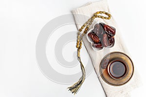 Ramadan Kareem Festival, Dates on wooden bowl with cup of black tea and rosary on white isolated background