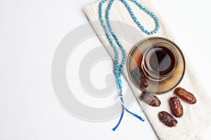 Ramadan Kareem Festival, Dates on wooden bowl with cup of black tea and rosary on white isolated background