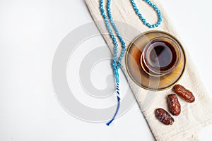 Ramadan Kareem Festival, Dates on wooden bowl with cup of black tea and rosary on white isolated background