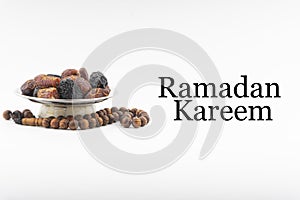 RAMADAN KAREEM text with Dates or kurma fruits and rosary beads or Tasbih on white background.