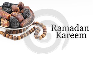 RAMADAN KAREEM text with Dates or kurma fruits and rosary beads or Tasbih on white background.