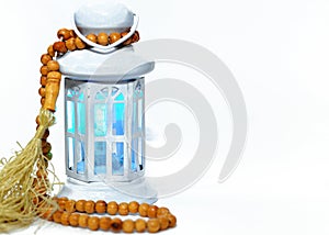 Ramadan lantern (fanoos) with an Islamic rosary around it isolated on a white background with a copy space for typing