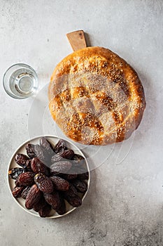 Ramadan pide, glass of water and date fruits on a gray background. Top view