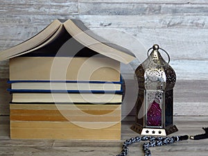 Ramadan Ramazan time celebration. A pile of home shaped old books, silver Ramadan lantern, black chaplet, worry-beads.