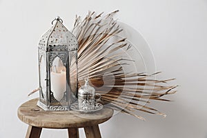 Ramadan still life. Silver Moroccan, Arabic lantern and cup of Turkish tea, coffee. Brown palm leaves on old wooden