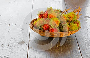 Rambutans fruit in basket on a wood desk background