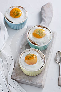Ramekins baked eggs on white background, top view
