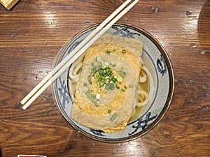 Ramen or Japanese noodles topping with deep fried tofu and scallions in clear soup