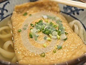 Ramen or Japanese noodles topping with deep fried tofu and scallions in clear soup