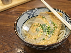 Ramen or Japanese noodles topping with deep fried tofu and scallions in clear soup