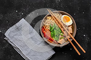 Ramen noodle soup with chicken, vegetables and eggs. Black rustic stone background. Top view. Japanese food.