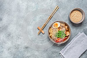 Ramen noodle soup with chicken, vegetables and eggs. Gray concrete rustic background. Top view. Japanese food.