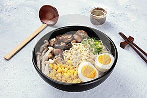 Ramen. Soba noodles with boiled eggs, mushrooms, and vegetables, with sake, wooden spoon, and chopsticks