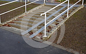 Ramp combined with a gray concrete staircase and a handrail specially adapted for wheelchairs. security tasteful solution for ente