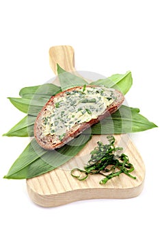 Ramson butter on slice of brown bread with fresh leaves.