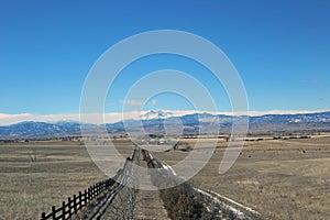 A ranch fence leading up to the rockies