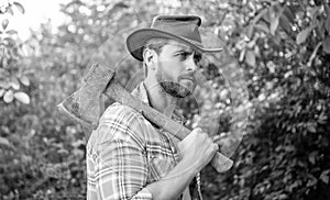 rancher with axe outside. rancher with axe wearing checkered shirt. rancher with axe