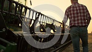 Rancher check field thresher reel farming vehicle at golden sunset countryside.