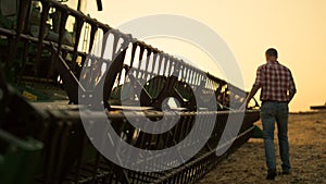 Rancher check field thresher reel farming vehicle at golden sunset countryside.